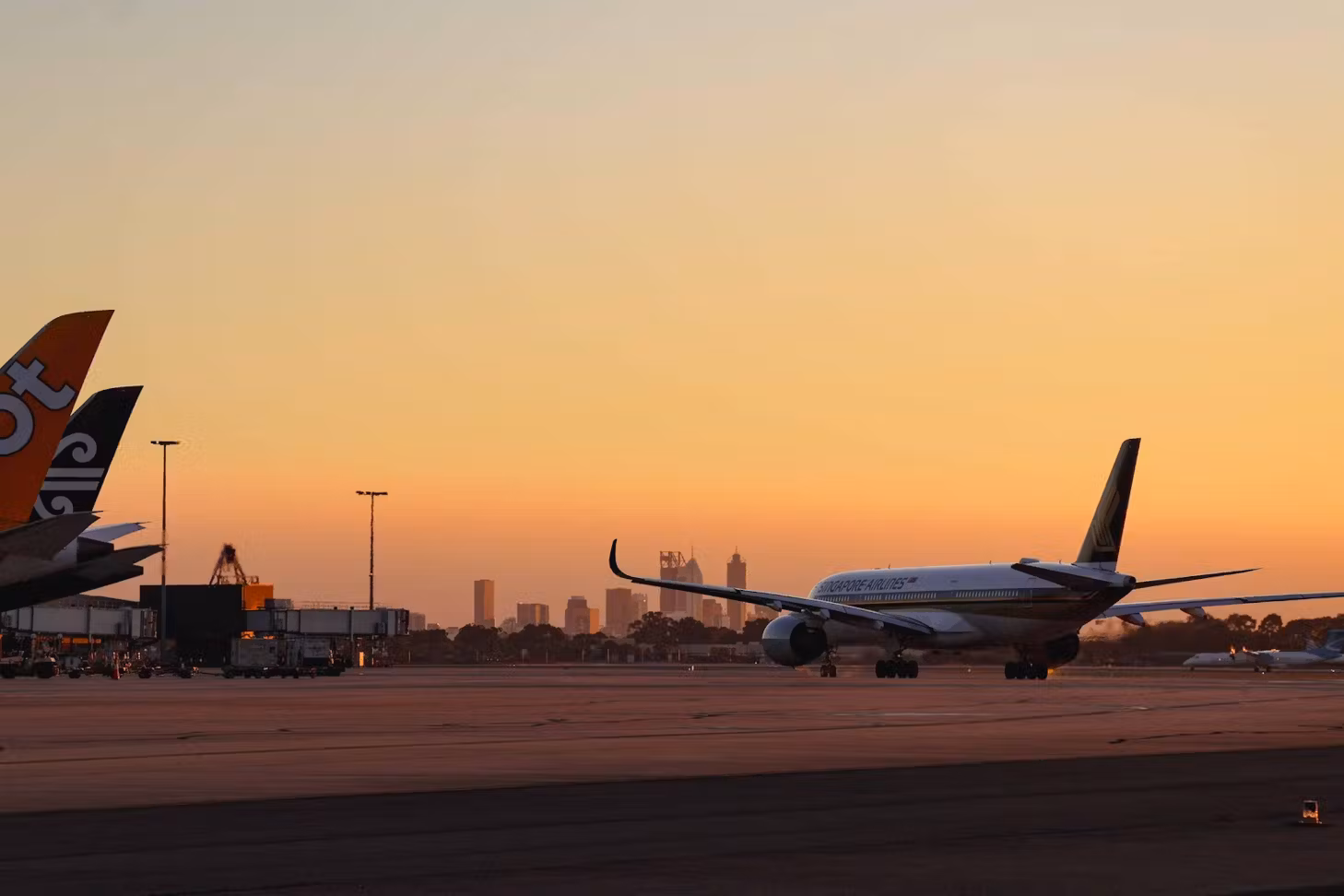 A wide shot of a plane beginning to prepare itself for take-off on the runway. It is either sunrise or sunset, and the sky is clear.